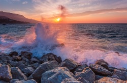 Landscape with waves crashing against the coastal stones at sunrise
