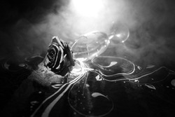 Broken wineglass and wilted rose on dark background. A wilting rose signifies lost love, divorce, or a bad relationship, dead rose on dark background with smoke. Selective focus