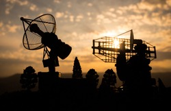 Silhouettes of satellite dishes or radio antennas against night sky. Space observatory or Air defence radar over dramatic sunset sky. Creative artwork decoration. Selective focus