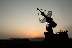 Creative artwork decoration. Silhouette air defence radar antenna during sunset. Satellite dishes or radio antennas against evening sky. Selective focus