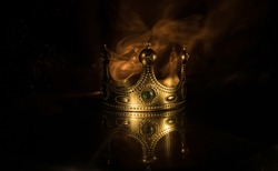 low key image of beautiful kings crown over wooden table. vintage filtered. fantasy medieval period. Selective focus. Colorful backlight