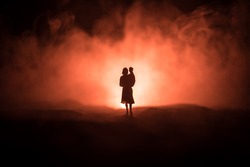 Silhouette of woman with child walking at cemetery at night. Horror Halloween concept. Artwork table decoration with light and smoke. Selective focus