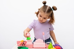 little girl plays in the store, scans and weighs vegetables on toy scales, children's cash register, closeup, children's home games concept
