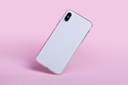 Smartphone in clear phone silicone case falls down, back view. iPhone X case mockup isolated on pink background