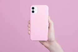 Female hand holding white iPhone 11 in soft silicone pink cover back view. Phone case mock up