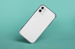 White iPhone 11 in clear silicone case falls down isolated on green background back view. iPhone 12 case mockup