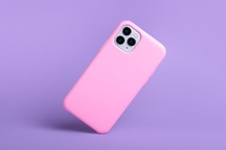 Smartphone iPhone 11 and 12 Pro max in pink silicone case falls down back view, phone case mockup isolated on purple background