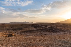 Beautiful dry landscape with colorful sand and cloudy blue sky. Sunset in the wilderness. The arid landscape of the prairie. Israel Negev Desert Sede Boker. Great view of the Nakhal Tsin rift. 
