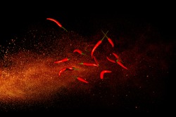 Hot red pepper on a background of ground pepper. Flying composition on black background