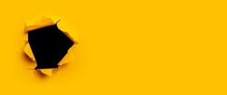 Bright yellow torn paper inside a black hole in a hole. Banner