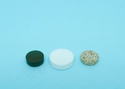 Green, white and mottled tablets lie on a blue background, copy space