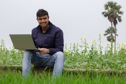Young farmer using laptop for at the agriculture field in rural area.