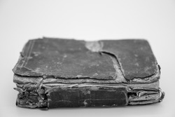 An Antique Book Sits Closed, Leather Cover And Spine Facing Us. Age has left the corners of the spine worn down, with the pages bundled together to hold the printed words within. 