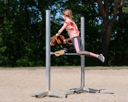 Girl jumping on hobby horse. Champion. Horse sport. Summer light. Green outdoor trees background. Child sport. Banner