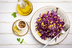 Fresh coleslaw salad made of shredded red and white cabbage and corn on white wooden background, top view