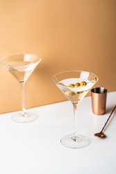 Cocktail vodka martini with green olives on orange background with bright beautiful shadows