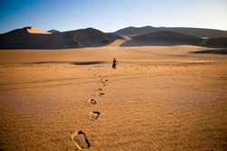Walking alone in the desert with footsteps