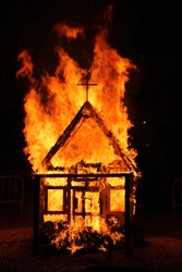 Church with cross burns in flames at dark night. It is a tradition in Spain at San Juan festival.