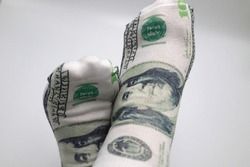 Crossed feet with one dollar bill socks growing Roth IRA 401k dividends stocks fund passive income portfolio investments cashing in and reaching financial economy and wealth success