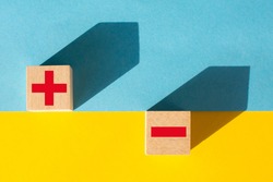 Symbols of red color plus and minus on wooden cubes on a yellow and blue background