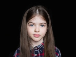 Closeup portrait of serious little girl isolated on black background
