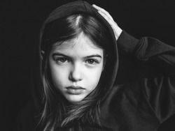 portrait of offended sad young girl on dark background, black and white photo, concept of problems of parents and children