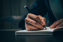 Close up of business people hand in suit writing on notebook or document