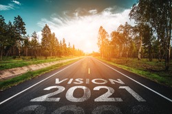 Vision 2021 written on highway road in the middle of empty asphalt road at golden sunset and beautiful blue sky. Concept for new year 2021.