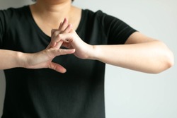Close-up of woman in black T-shirt is cracking her knuckles; after working hard that using hand and fingers; or gesturing like ready for doing something; concept of health care and medical. 