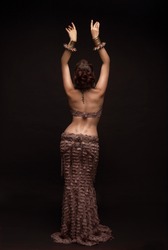 Oriental beauty with a slender figure and a narrow waist. View from the back . Hands raised up.