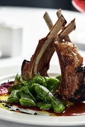 Grilled rack of lamb, close-up. Lamb bone medallions from the chef, tender lamb meat on a light plate with garnish