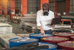 businessman wearing a mask to prevent toxic chemicals enters a warehouse in a factory for flammable hazardous substances.