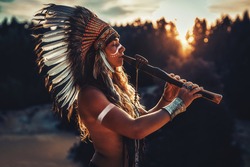beautiful shamanic girl playing on shaman flute in the nature.