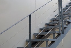 Outdoor metal stairway with handrails closed to a house wall going to upstairs
