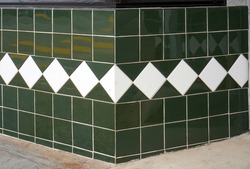 Vintage green tile wall with white diamond tile accents.                         
