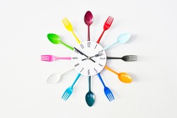 A kitchen wall colorful clock, decorated with bright tableware: spoons and forks