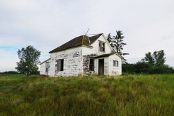 Old white abandoned house in the middle of a field in Saskatchewan, Canada.