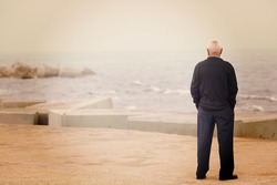 A man looking at the sea on the dock. Image has a vintage effect.