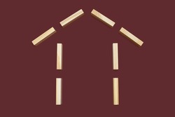 House shape from wooden rectangles on a brown background. The concept of building or buying your own home. Game for children from wooden rectangles