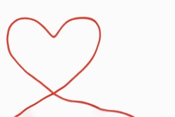Red rope in the form of a heart on a white isolated background. The concept of love in the form of a folded red rope in the shape of a heart. Top view of a red thread heart. Free space for text