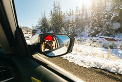 girl takes pictures of herself through a car mirror. car rides through winter forest
