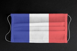 Coronavirus update in France. French healthcare concept. Flag of France printed on medical mask on black background. Covid-19 outbreak.  Spread of corona virus in Europe.