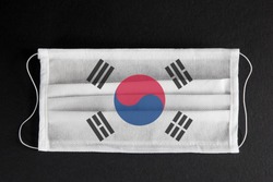 Coronavirus update in South Korea. South Korean healthcare concept. Flag of South Korea printed on medical mask on black background. Covid-19 outbreak.  Spread of corona virus in Asia.