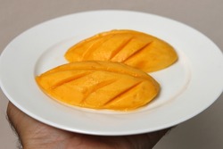 Fresh organic ripe mango fruit on white plate. The fiber, potassium and vitamin content in mangoes help keep the arteries working and reduce the risk of heart disease.