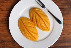 Fresh organic ripe mango fruit on white dish. The fiber, potassium and vitamin content in mangoes help keep the arteries working and reduce the risk of heart disease.