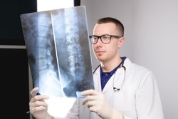 surgeon examines x-ray. spinal x-ray. health problems. nurse checking x-ray in hospital. An experienced male doctor interprets an x-ray. man looks.