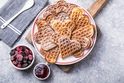 Freshly baked homemade heart shaped Belgium waffles  on gray background. European baked pastry sweets.  St. Valentine's Day breakfast concept.