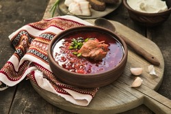 Borscht - Traditional Ukrainian dish.  Vegetable soup made from beets, potatoes, cereals and boiled meat, and  slices of rye bread in a ceramic bowl on a wooden kitchen table. Russian  food cuisine