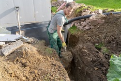A man Digging ground to prepare for drainage home.