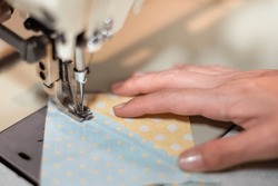 Closeup of the female hand use a sewing machine and cotton fabric at the old sewing machine with vintage style.